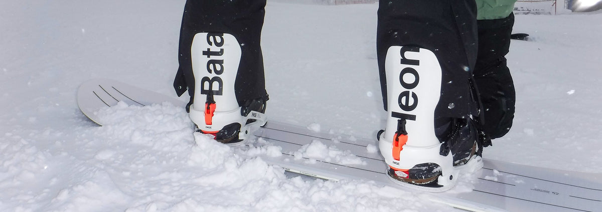 the back of the bataleon snowboard bindings being displayed in fresh snow while strapping in the bataleon bindings